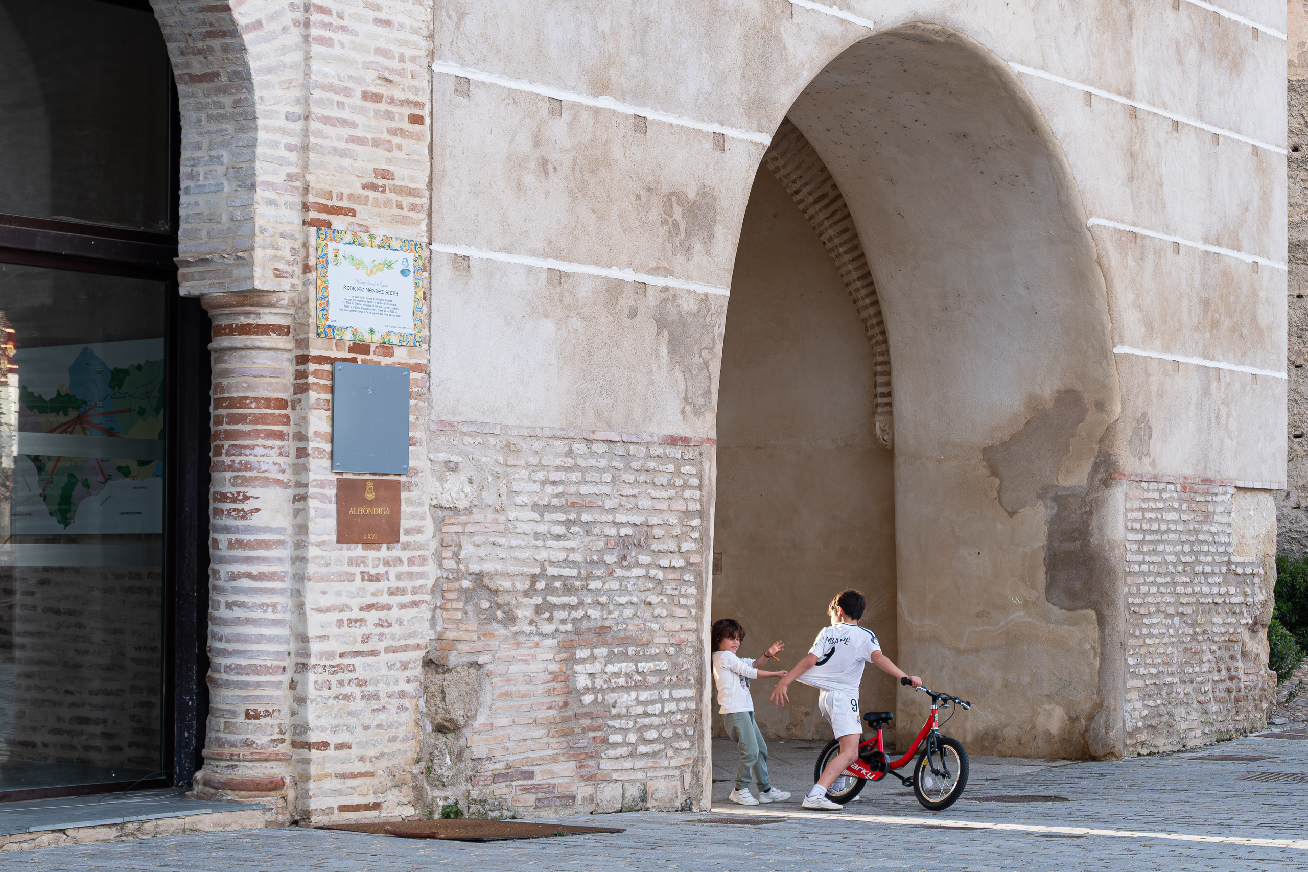 Kinder spielen an einem alten Stadttor-Bogen